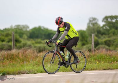 High-performance cyclist riding on a rural road, promoting Bluebonnet Express bike services.