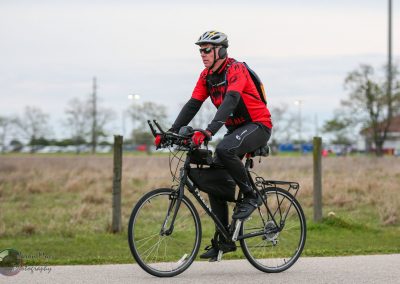 Comfortable cyclist riding an e-bike in outdoor park with Bluebonnet Express branding visible.