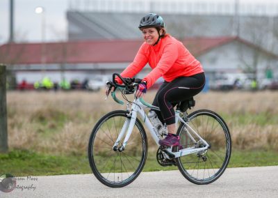 Bright woman cycling on a trail, promoting Bluebonnet Express with eco-friendly transportation.