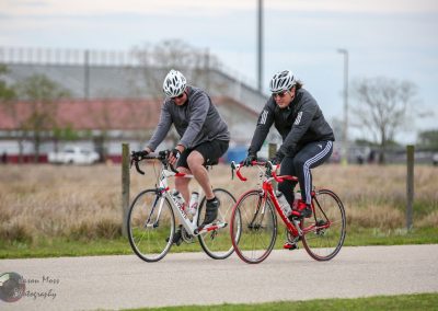Two cyclists riding on a bike path during daytime, promoting outdoor biking and fitness.