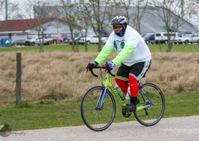 Bright green and yellow bicycle with rider in athletic gear on pavement, participating in Bluebonnet Express event.