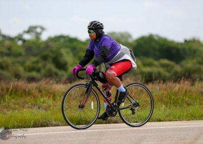 Bright cyclist riding a road bike outdoors with lush greenery in the background, emphasizing adventure and eco-friendly transportation.