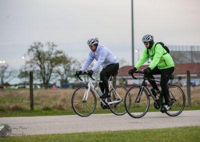 Brightly dressed cyclists riding e-bikes outdoors on a cloudy day for eco-friendly commuting.