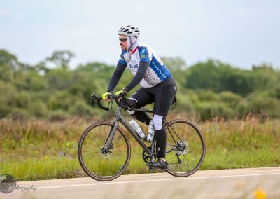 High-performance cyclist riding on scenic open road, promoting Bluebonnet Express cycling event.