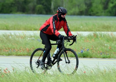 Vegan cyclist riding on a scenic outdoor trail surrounded by wildflowers and greenery.