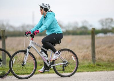Bright blue outdoor cycling jacket worn by woman riding mountain bike on scenic trail.