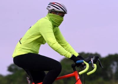 Vibrant cyclist wearing neon green jacket and face covering riding a red bike outdoors.