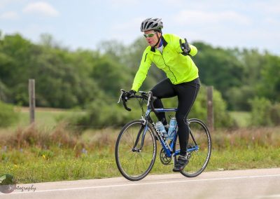 Bright yellow cycling jacket on a man riding a bike on a scenic outdoor trail.