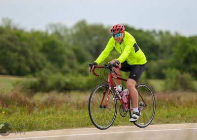 Bright yellow athletic jacket, cyclist enjoying outdoor ride on red bike in nature.