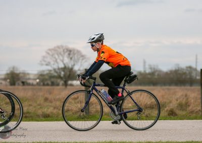 Bright orange cycling jersey, cyclist riding a Cannondale road bike during daytime.