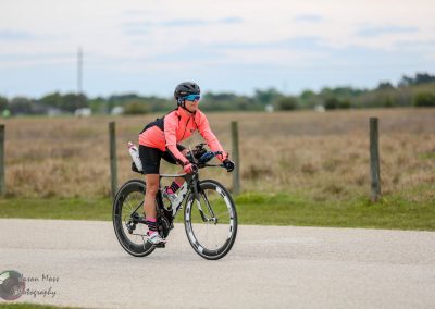 Vast open landscape with female cyclist riding a bike, promoting Bluebonnet Express cycling events.