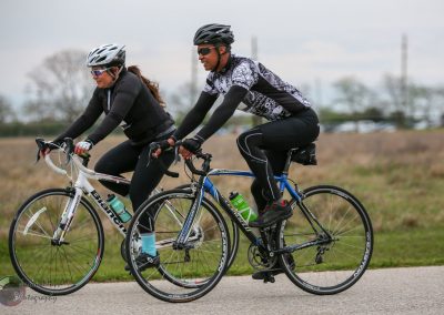 High-performance cyclists riding bicycles outdoors on a scenic trail, representing Bluebonnet Express cycling team.