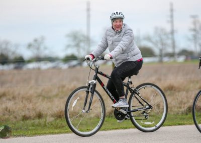 Relaxed woman cycling outdoors on a cloudy day, Bluebonnet Express bike ride, Texas bike trail adventure.