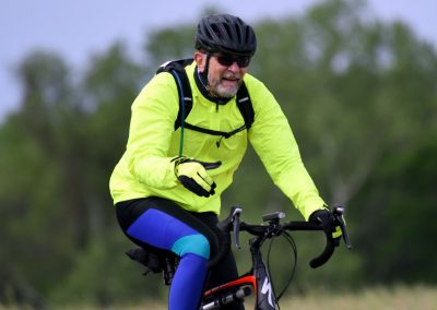 Vibrant cyclist wearing high-visibility gear riding on a trail, emphasizing the Bluebonnet Express biking experience.