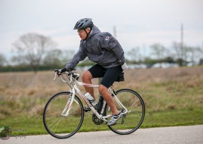 Bike courier riding on a paved path with a gray jacket and helmet.