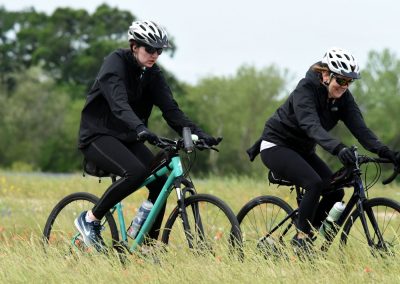 Women cycling on mountain bikes in a scenic outdoor setting, enjoying an active ride.