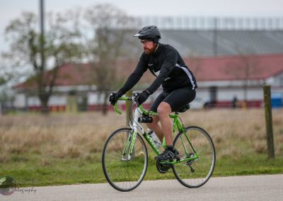 High-performance cyclist riding green and white bike, Bluebonnet Express outdoor cycling event, Texas scenic trail.