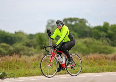 Bright yellow cycling jacket on female cyclist riding a red bike outdoors during daytime.