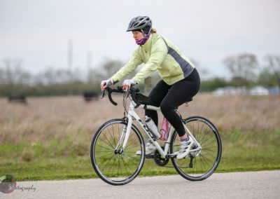 Bright woman riding a bicycle outdoors, wearing helmet and activewear for fitness and recreation.