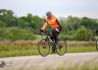Bright cyclist riding on scenic trail in outdoor setting, representing Bluebonnet Express biking event.