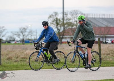 Cyclists riding bikes outdoors with helmets, promoting Bluebonnet Express cycling event and health benefits.