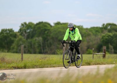 Bright green cycling jacket on cyclist riding a road bike outdoors in nature.