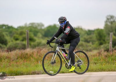 Bright yellow cycling shoes with blue accents on a cyclist riding on a rural road.