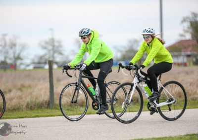 Bright neon cyclists riding on a scenic trail, showcasing Bluebonnet Express eco-friendly bike service.