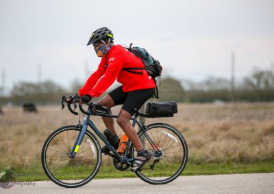 High-performance cyclist riding a blue electric bike on scenic outdoor trail.