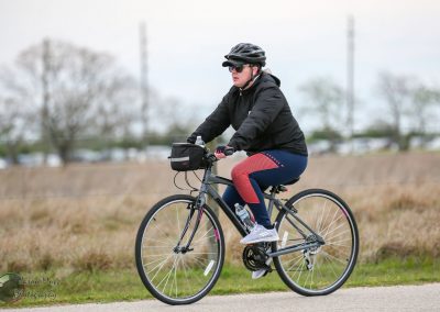Comfortable cyclist riding Bluebonnet Express bike on paved trail during cloudy day.