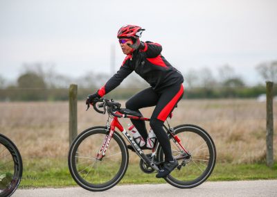 Bright red and black cycling gear on cyclist riding mountain bike outdoors during overcast day.