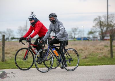 Cyclists riding bikes outdoors in cool weather during daytime.