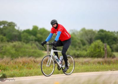 Bike rider in red shirt on a scenic outdoor trail representing Bluebonnet Express cycling event.