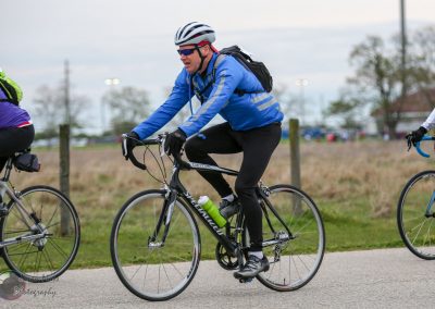Vibrant cyclist riding a bike outdoors during daytime, promoting Bluebonnet Express bicycle services.