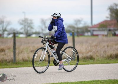 Bike rider in blue jacket participating in Bluebonnet Express cycling event, wearing helmet and gloves.