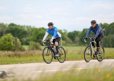 Bright blue bikes riding along a scenic countryside trail during daytime, promoting Bluebonnet Express cycling event.
