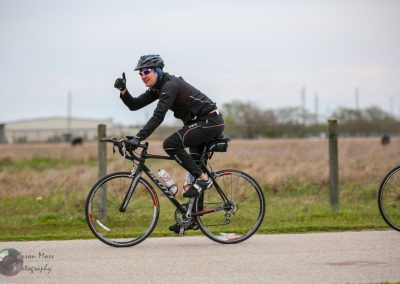 Bike rider giving a thumbs-up during a cycling event on a rural road Bluebonnet Express.