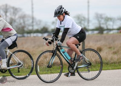 Young woman cycling outdoors with a hydration bottle on a scenic bike ride in Texas.