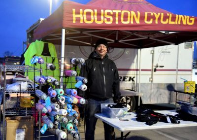 Brightly colored cycling water bottles at Houston Cycling event booth, outdoor scene.
