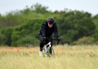Vibrant cyclist riding on a grassy field with lush green trees in the background, promoting outdoor biking adventures.