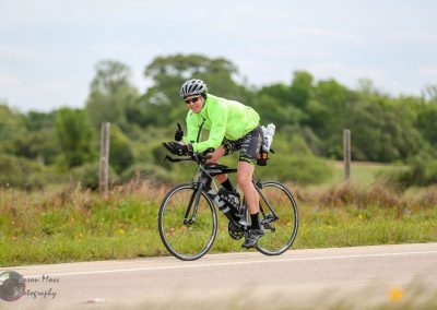 Vibrant cyclist in neon green riding on a scenic countryside road during daytime.