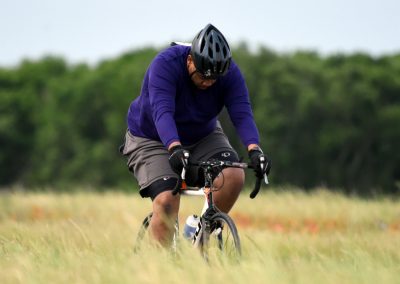 Energetic cyclist riding mountain bike through grassy field in outdoor setting.