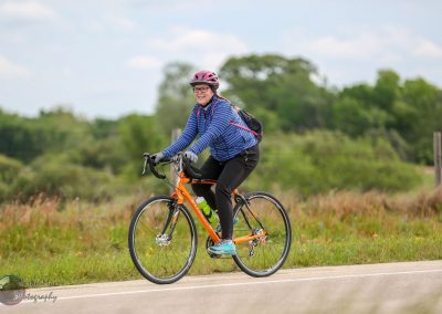 Bright woman riding a bicycle on a scenic trail in Texas during daytime.