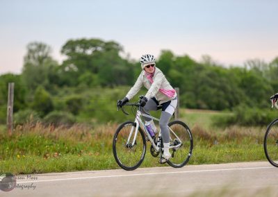 Woman riding a bicycle on a rural bike trail, enjoying outdoor activity in nature.