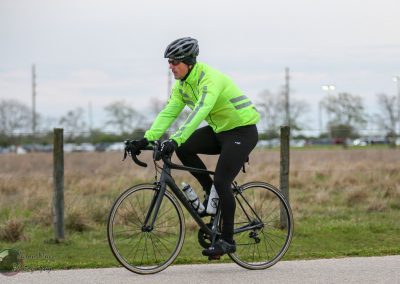 High-visibility cyclist riding on a paved trail in outdoor setting for safe biking.