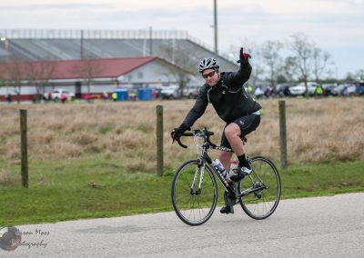 Man cycling on paved trail during Bluebonnet Express event, wearing helmet and cycling gear.