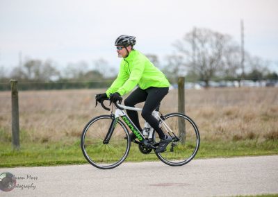 Bright green cycling jacket on a cyclist riding a Cervélo road bike outdoors.