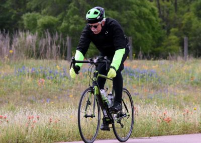 Vibrant cyclist riding a bike through wildflower meadow in spring, promoting eco-friendly outdoor activities.