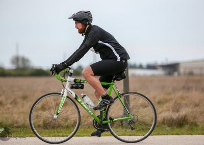 Bright green and white Trek hybrid bicycle on paved trail with a male cyclist in black gear, helmet, and casual riding attire.