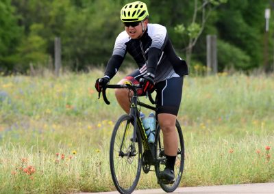 High-performance cyclist riding on a scenic trail with greenery and wildflowers.